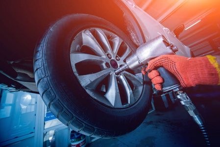 專業的汽車修理工在汽車維修服務的氣動扳手工作。車輪修理